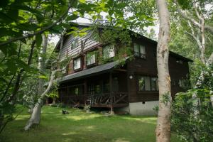 a large wooden house in the middle of trees at Okushiga Lodge Yama no Manimani in Yamanouchi