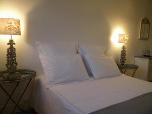 a white bed with white pillows and two lamps at Les chanceliers Duplex in Beaune