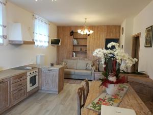 a kitchen and living room with a table with white flowers at Al Salgiar in Tuenno