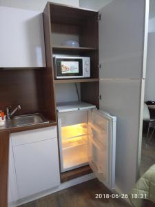 a small kitchen with a refrigerator and a microwave at Apartament MEGAPOLIS & RADIUS in Yekaterinburg
