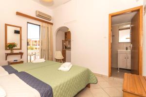 a bedroom with a green bed and a bathroom at Oriental Bay in Palaiochora