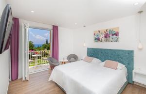 a white bedroom with a bed and a balcony at Boutique Flamingo B&B in Mlini