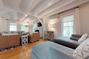 a living room with a couch and a living room with windows at #OB Pool House in Oak Bluffs