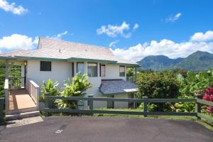 a house with a fence and mountains in the background at Hanalei Bay Villas #33 in Princeville