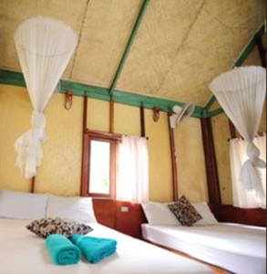 Pokój z 2 łóżkami z niebieskimi poduszkami w obiekcie Smile Bungalow Bottle Beach w mieście Bottle Beach