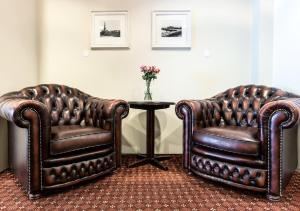 トロンハイムにあるChesterfield Hotelの革張りの椅子2脚、花瓶付きテーブル