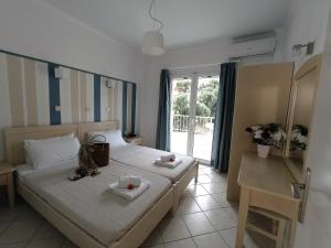 a hotel room with two beds and a window at Filanthi Apartments in Paralia Vrachou