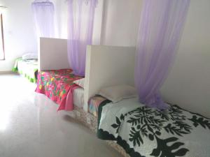 2 Betten in einem Zimmer mit lila Vorhängen in der Unterkunft Bali Sari Homestay in Amed