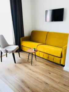 a yellow couch in a living room with a table and a chair at Apartments 110 in Budva in Budva