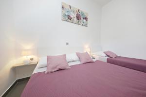 two beds in a room with pink and white sheets at Apartmani Rudi in Vir