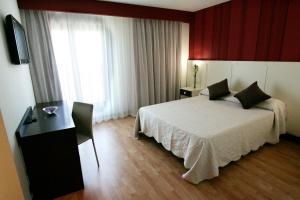 a bedroom with a bed and a desk and a window at Hotel La Bastida in Toledo