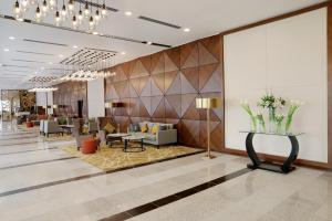 a lobby with a waiting area with chairs and tables at Millennium Madinah Airport in Al Madinah