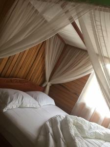 a canopy bed with white sheets and a window at Villa Bella in Tondano
