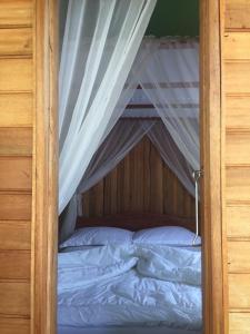 a bedroom with a canopy bed with white sheets at Villa Bella in Tondano