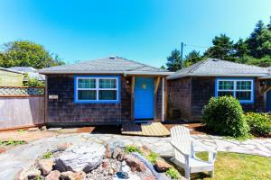 a house with a blue door and a chair in a yard at Hidden Villa Cottages in Cannon Beach
