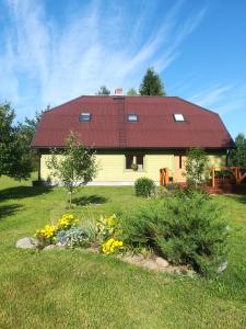 een geel huis met een rood dak en wat bloemen bij Kõrgemäe puhketalu in Eoste