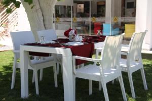 a white table with white chairs and a red table cloth at AELBİSTAN OTEL in Didim
