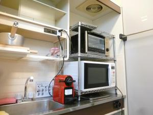 eine Küche mit Mikrowelle und Spüle sowie einen TV in der Unterkunft Nagoya Motoyama House C in Nagoya