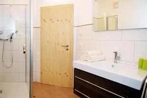 a bathroom with a sink and a shower with a mirror at Pension Biobauernhof Hinteraltensberg in Auffach