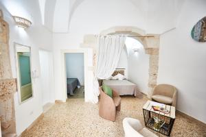 a white room with a bed and a chair and a table at EQUORUM 13 - Ostuni Centro in Ostuni