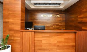 a reception desk with a sign on a wooden wall at Treebo Trend Durga Boji Grand Gonikoppal Town in Gonikoppal