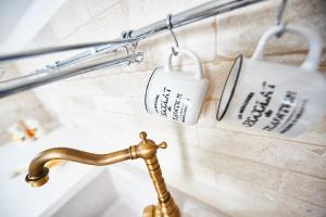 a bathroom sink with a faucet and two cups at EQUORUM 13 - Ostuni Centro in Ostuni +42 photos