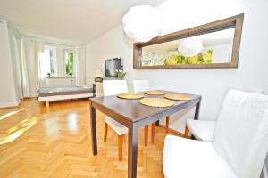 a dining room with a table and white chairs at Grand Apartments Tulipan in Sopot