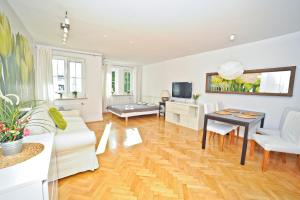 a living room with white furniture and a wooden floor at Grand Apartments Tulipan in Sopot
