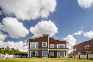 a brick house with clouds in the sky at Smėlynas Klaipėda Lake House in Klaipėda
