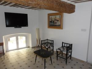 uma sala de estar com duas cadeiras e uma televisão na parede em La Maison des Augustines em Marselha