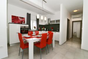 une cuisine avec une table blanche et des chaises rouges dans l'établissement Villa Luna - beautiful, modern and luxurious, à Pula
