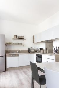 a kitchen with white cabinets and a table with chairs at Aux Iles d'Or in Hyères