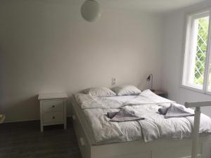 a white bedroom with a bed and a window at Balatonszemes small House in Balatonszemes