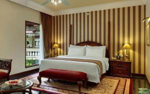 um quarto com uma cama grande e um banco vermelho em Mayfair Lagoon em Bhubaneshwar