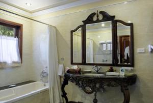 a bathroom with a sink and a mirror and a tub at Mayfair Lagoon in Bhubaneshwar