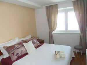 ein Schlafzimmer mit einem Bett mit Kissen und einem Fenster in der Unterkunft House Marija in Brela