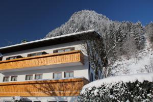 a building in the snow with a mountain in the background at Hotel Kienberger Hof in Pfronten