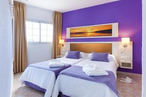 Dos camas en una habitación de hotel con paredes moradas. en Checkin Bungalows Atlántida, en Los Cristianos 37 fotos más