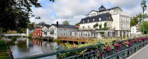 a group of buildings next to a river with flowers at Åtellet Hotell in Norrtälje