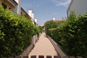 einen Backsteinweg zwischen Büschen und einem Gebäude in der Unterkunft Appartamenti in Residence Portosole e Residence Tamerici con piscina-Cavallino Treporti in Cavallino-Treporti