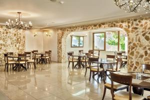 a restaurant with wooden tables and chairs and a chandelier at Adelais Hotel in Tavronitis