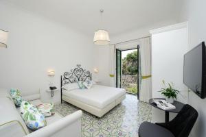 a white bedroom with a bed and a tv at Villa Guarracino Amalfi in Amalfi
