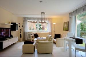 ein Wohnzimmer mit weißen Möbeln und einem großen Fenster in der Unterkunft FeWo im Grünen mit Terrasse und Garten - gratis Therme in Bad Bevensen