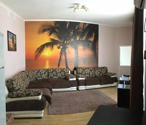 a living room with a couch and a palm tree mural at Гостевой дом Райское Местечко in Lazarevskoye