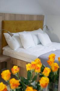 a bed with white pillows and a bunch of yellow flowers at Jaskółka - pokoje i apartament przy plaży in Olsztyn