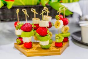 a fruit appetizer on a wooden board with strawberries and bananas at Ossuna Bay Hotel Boutique in Cefalù