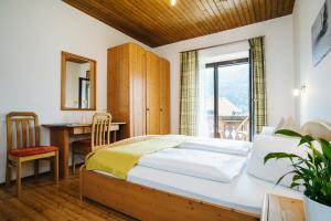 una camera da letto con un letto, una scrivania e una finestra di Ferienhof Hoffmann a Weissensee