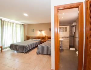 a hotel room with two beds and a bathroom at Hotel El Tablazo in Villalba de la Sierra