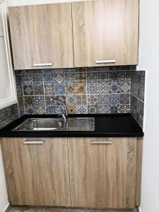 a kitchen with wooden cabinets and a sink at Cheerful Apartment in Nicosia in Yukarı Lakatamya