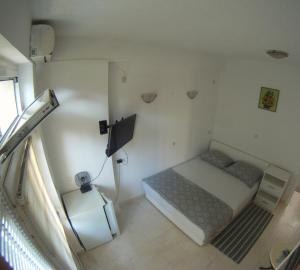 um pequeno quarto com uma cama e uma televisão em Salona suite em Solin